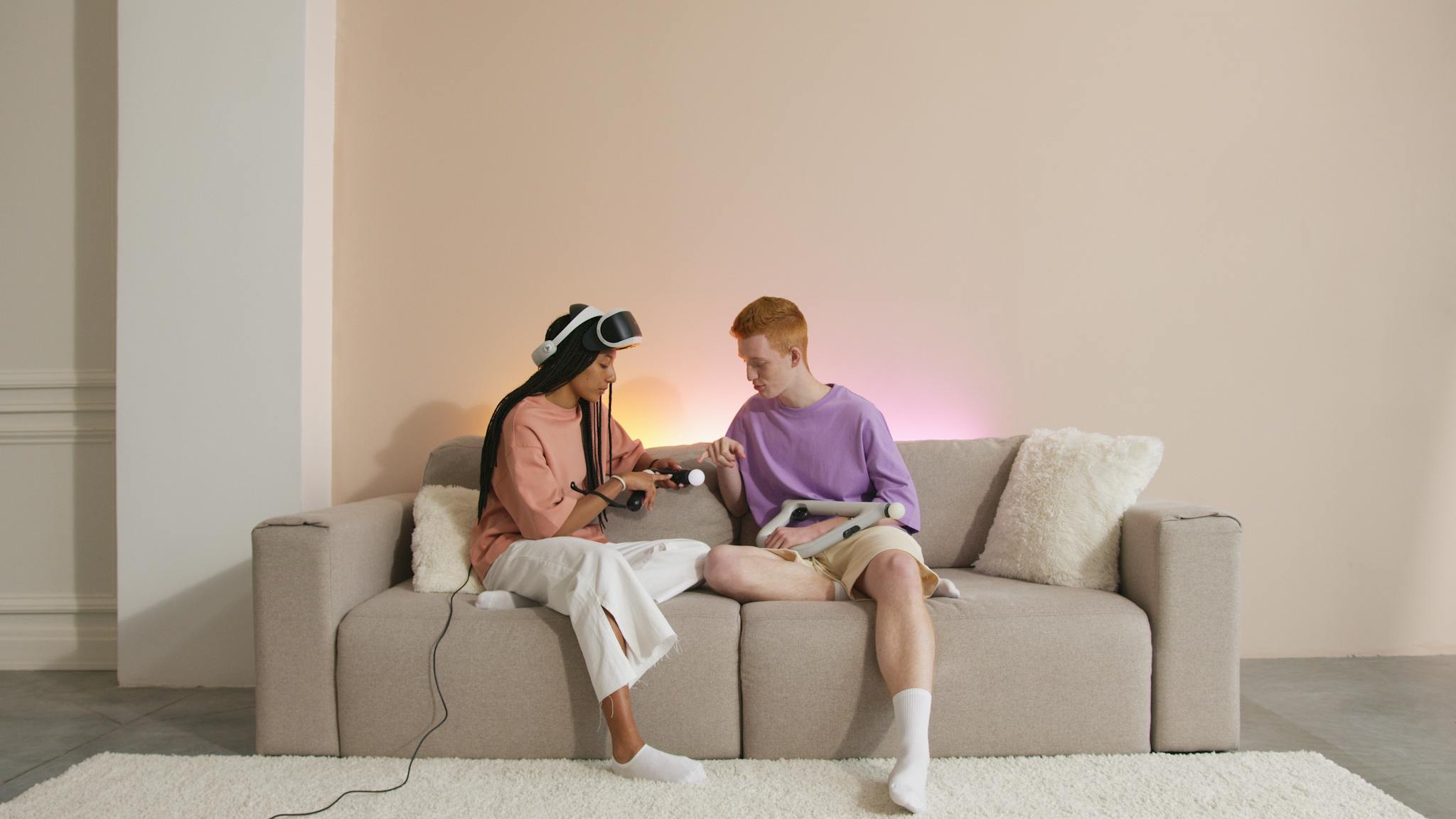 A diverse couple sitting on a sofa, playing with VR controllers indoors.