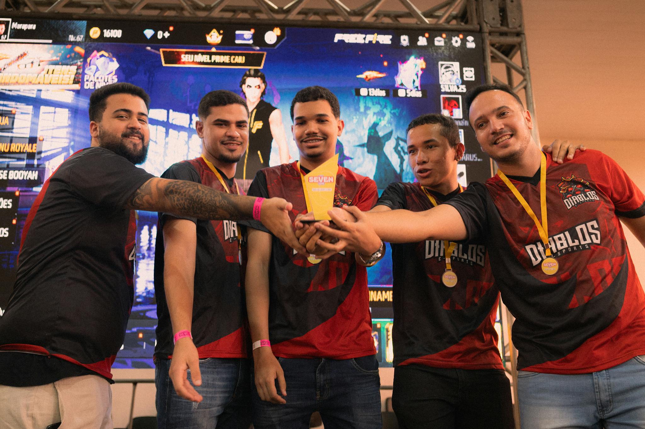 A group of gamers celebrating their victory at an e-sports event holding a trophy.